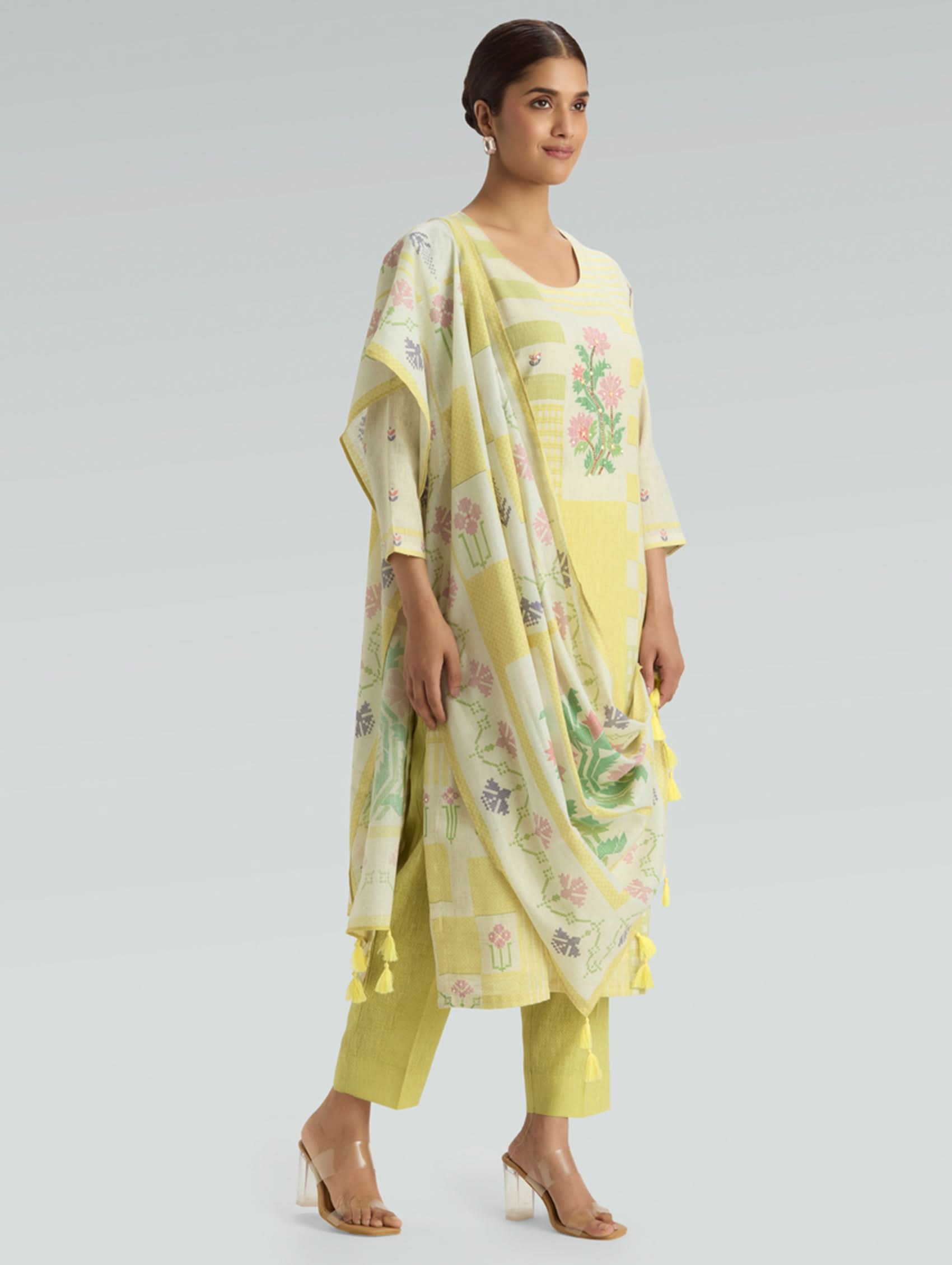 Woman wearing a yellow floral outfit with a matching dupatta on a light gray background