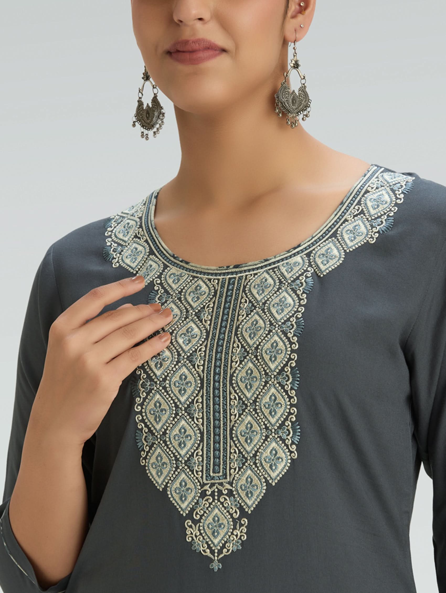 Woman wearing a gray outfit with a patterned Dupatta on a light gray background