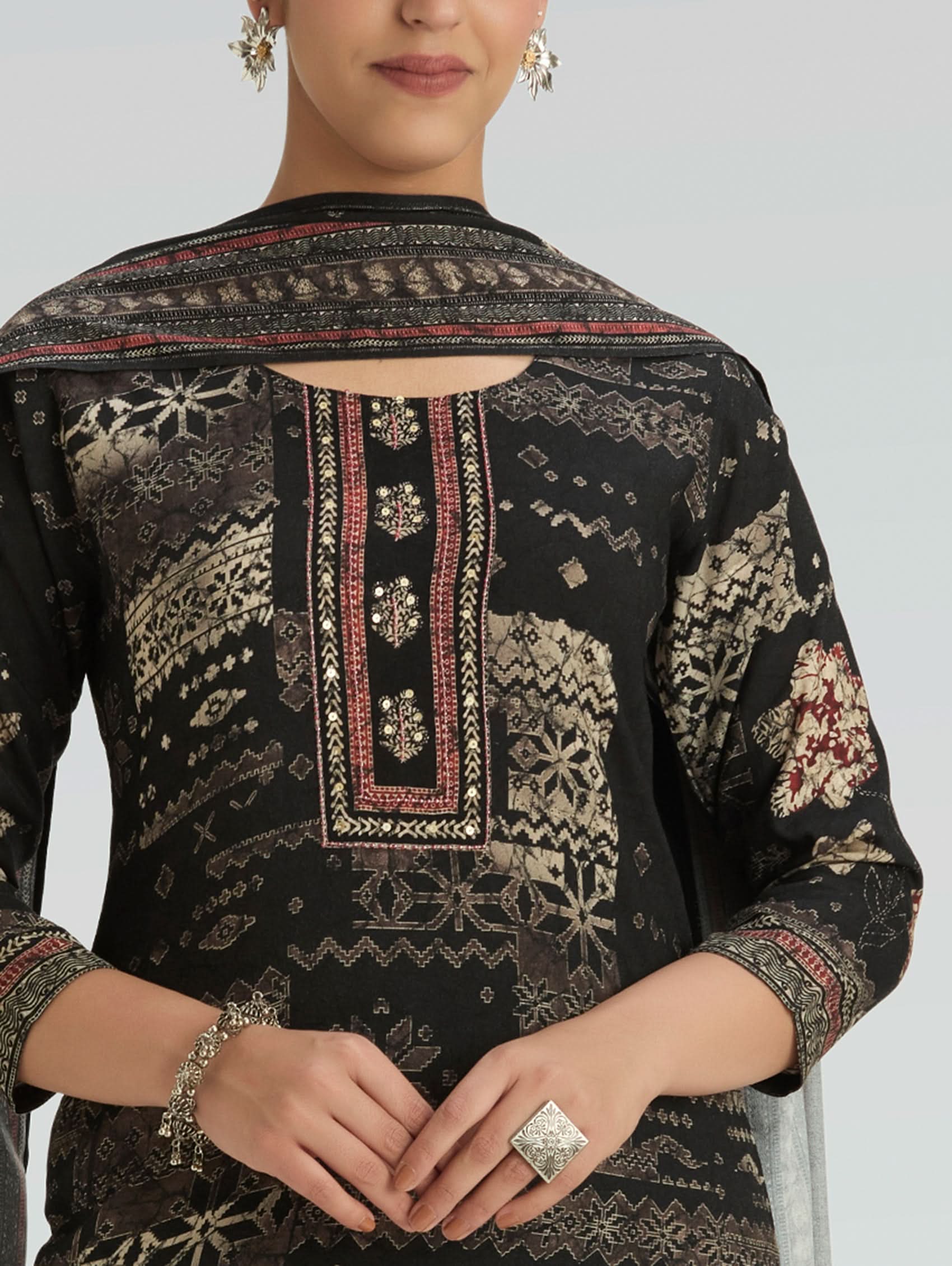 Black embroidered traditional outfit with intricate patterns on a plain background