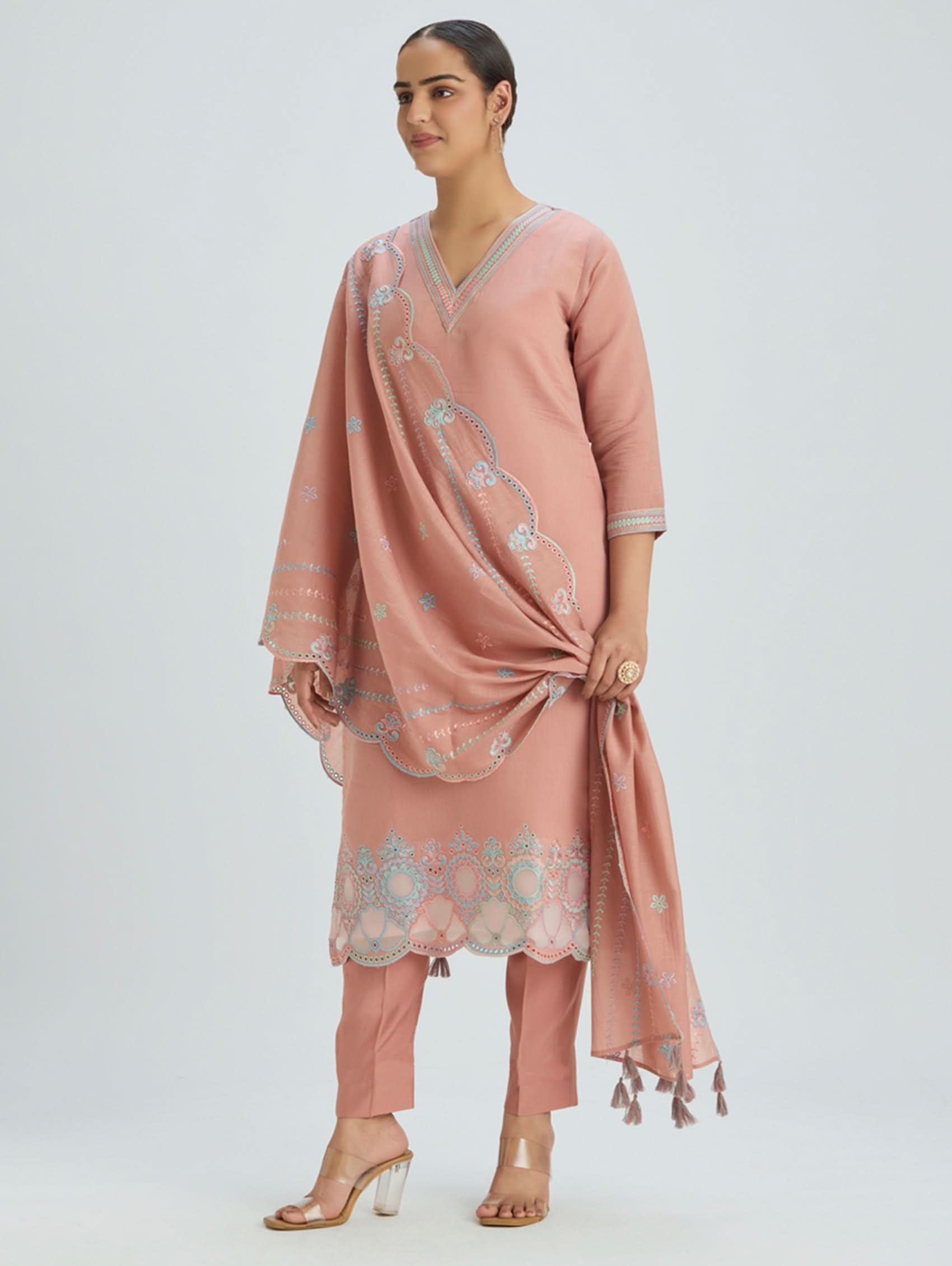 Woman wearing a pink traditional outfit with a matching dupatta on a white background