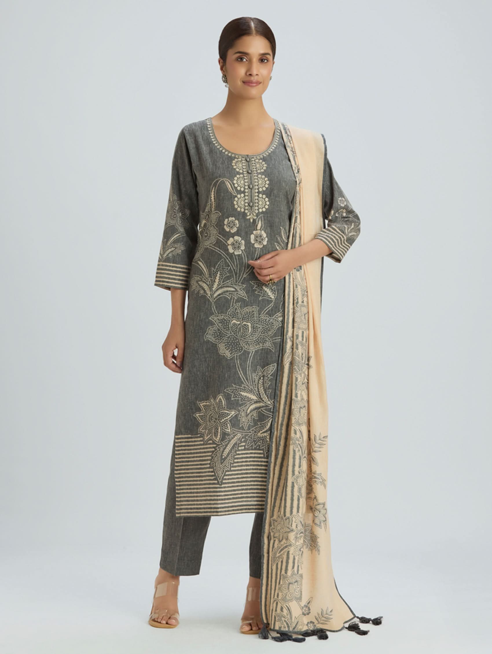 Woman wearing a gray floral embroidered outfit with a beige dupatta on a white background