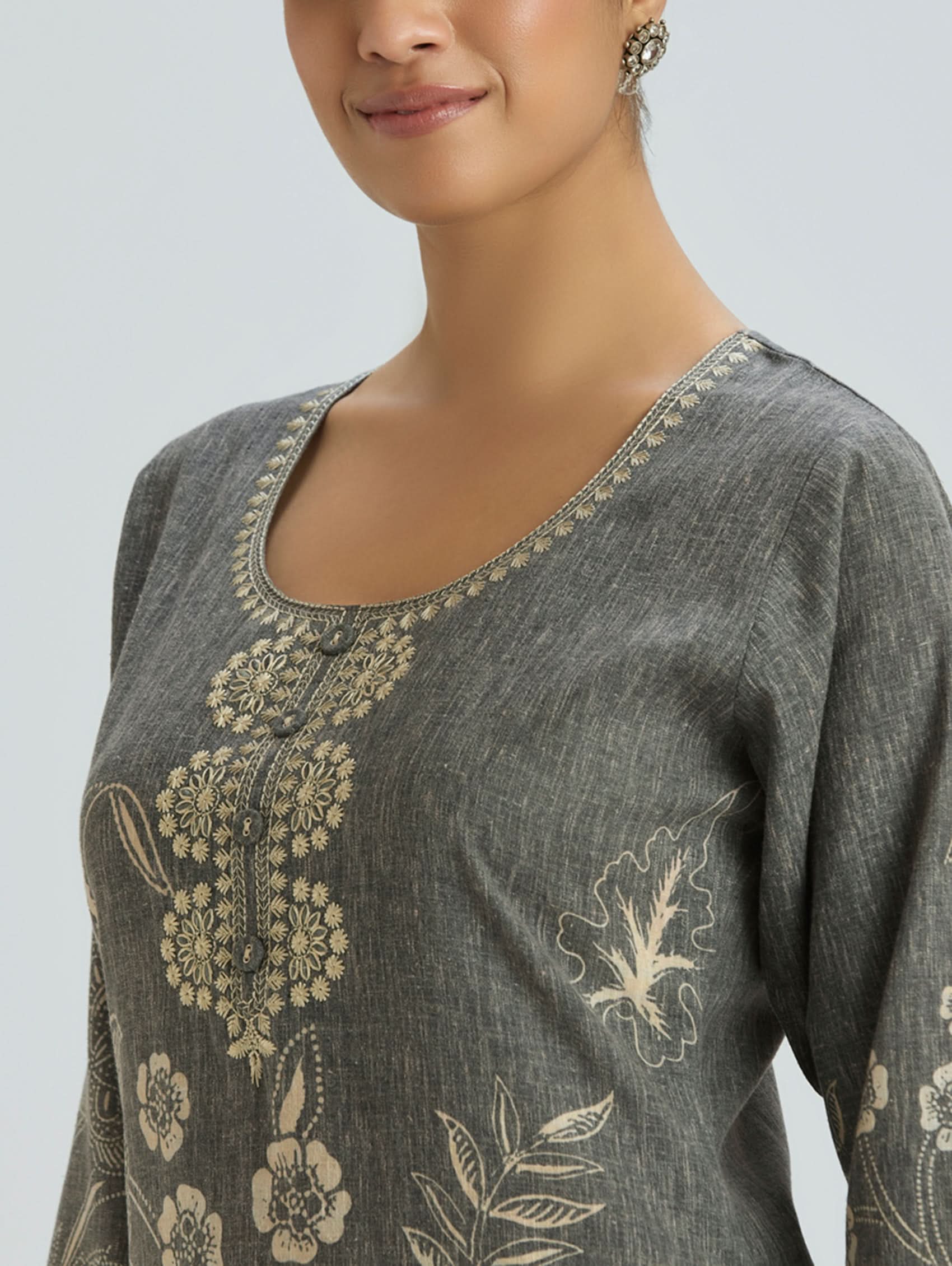 Gray embroidered top worn by a model on a light gray background