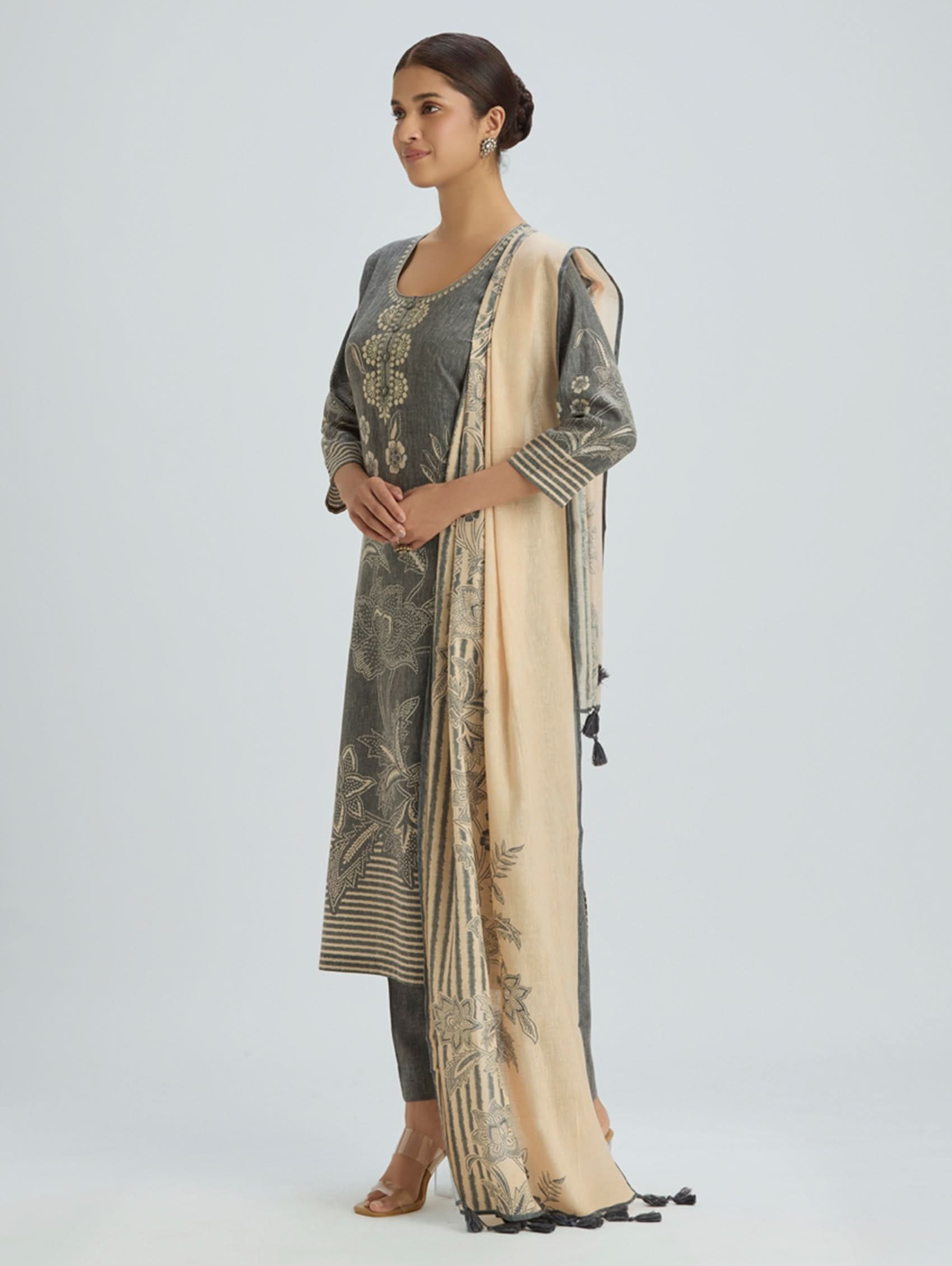 Woman wearing a traditional outfit with a long embroidered jacket and beige dupatta on a light gray background