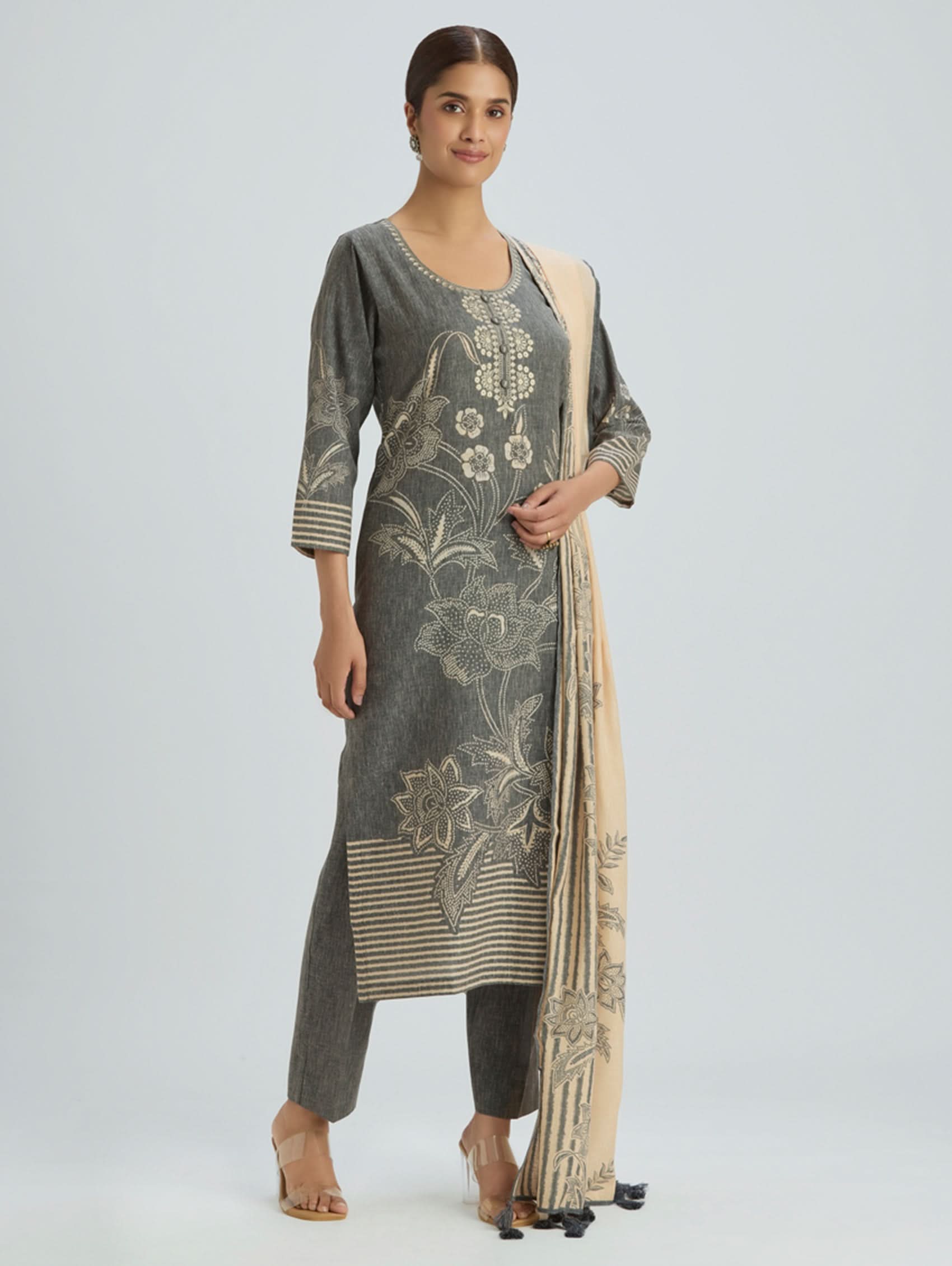 Woman wearing a gray and beige embroidered outfit on a white background