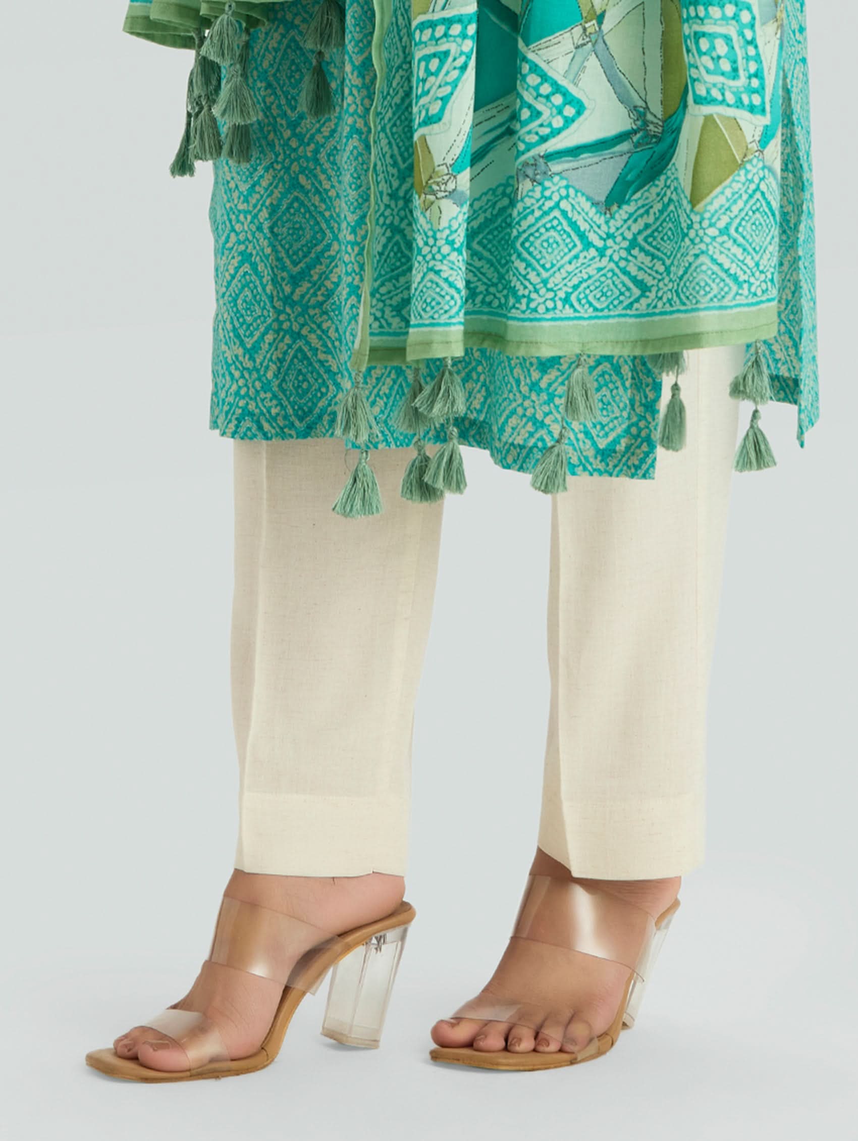 Teal patterned dupatta with tassels over a cream outfit on a light gray background