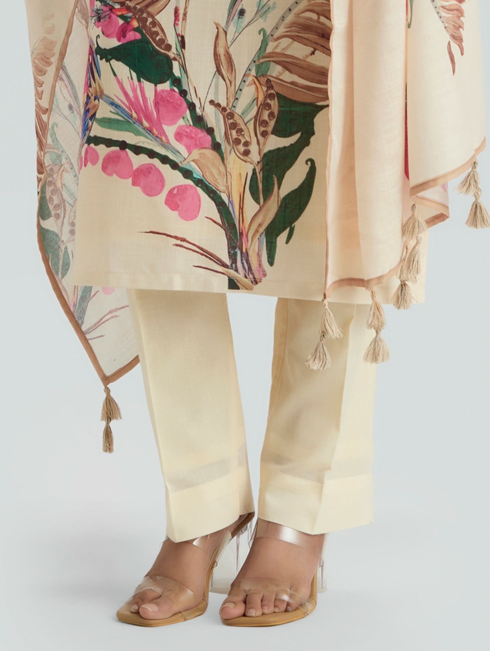 Beige outfit with floral patterned cover-up and tassels on a white background