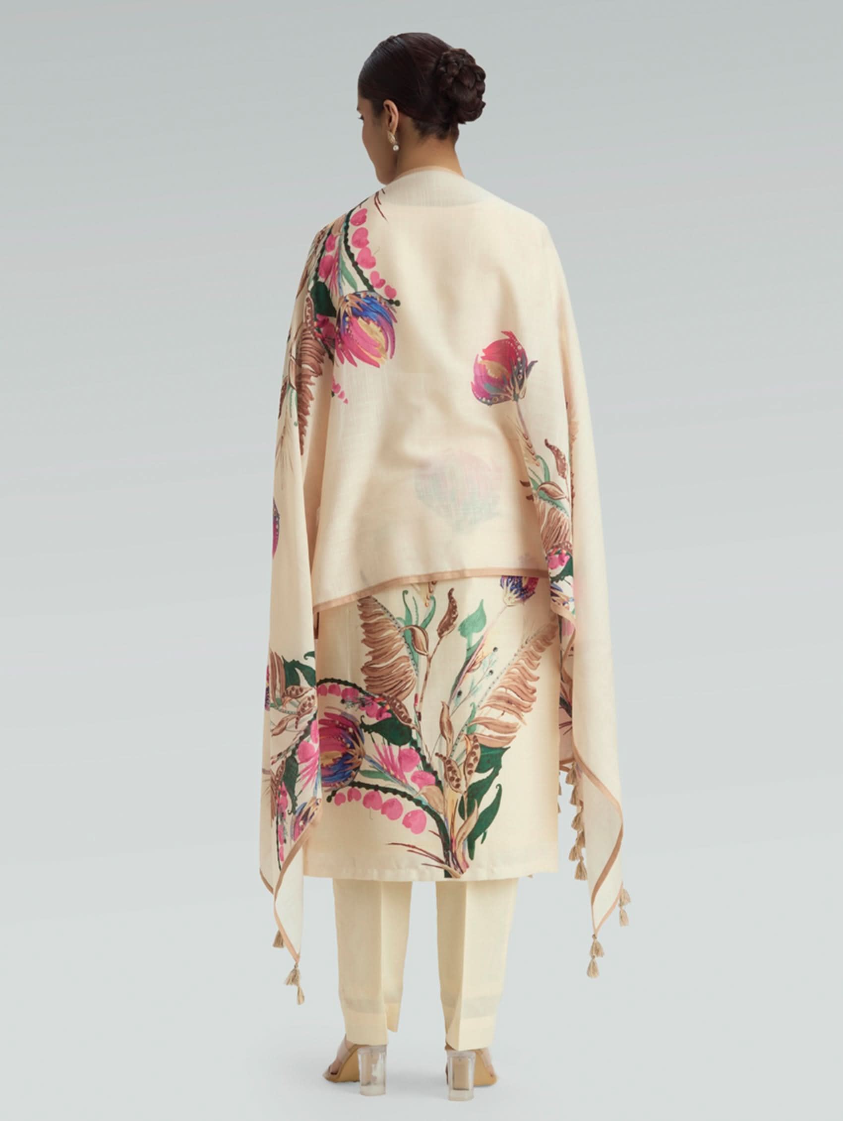 Person wearing a beige outfit with floral patterns on a plain background
