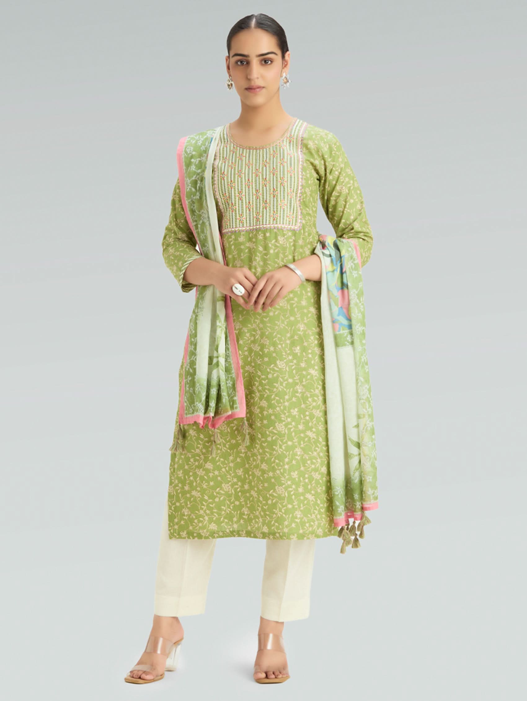 Woman wearing a green traditional outfit with a scarf on a gray background