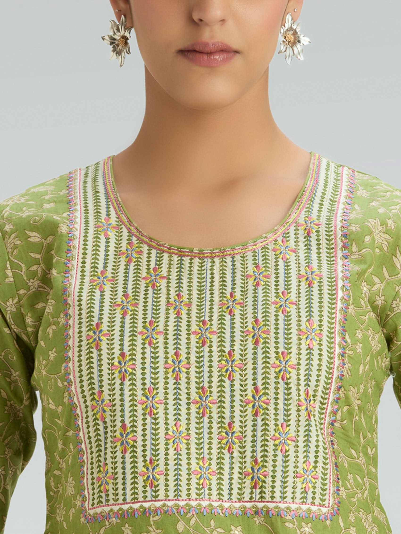 Green embroidered top worn by a person on a gray background