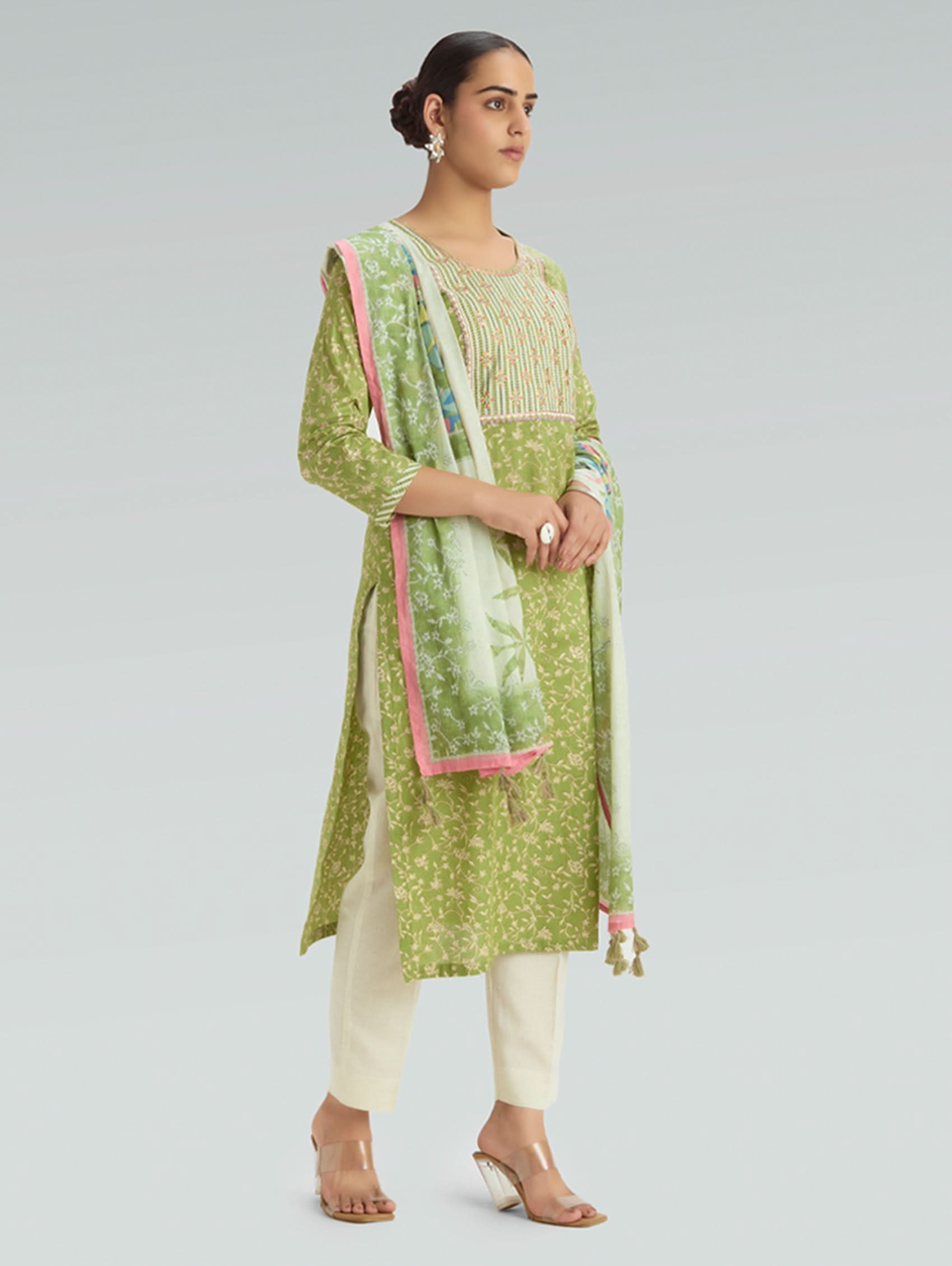 Woman wearing a green and white traditional outfit with a light gray background