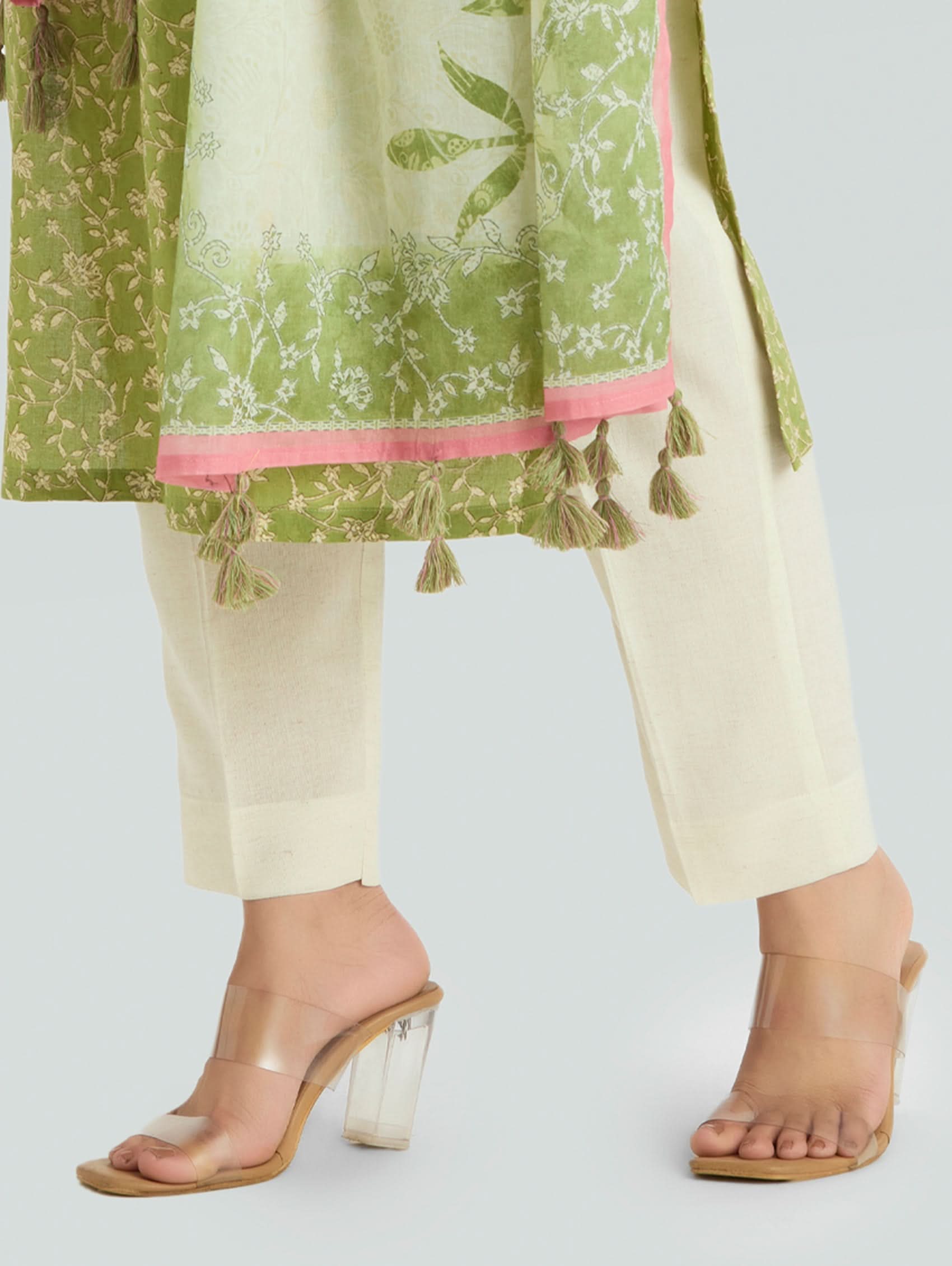 Green and white traditional outfit with tassels on a light gray background