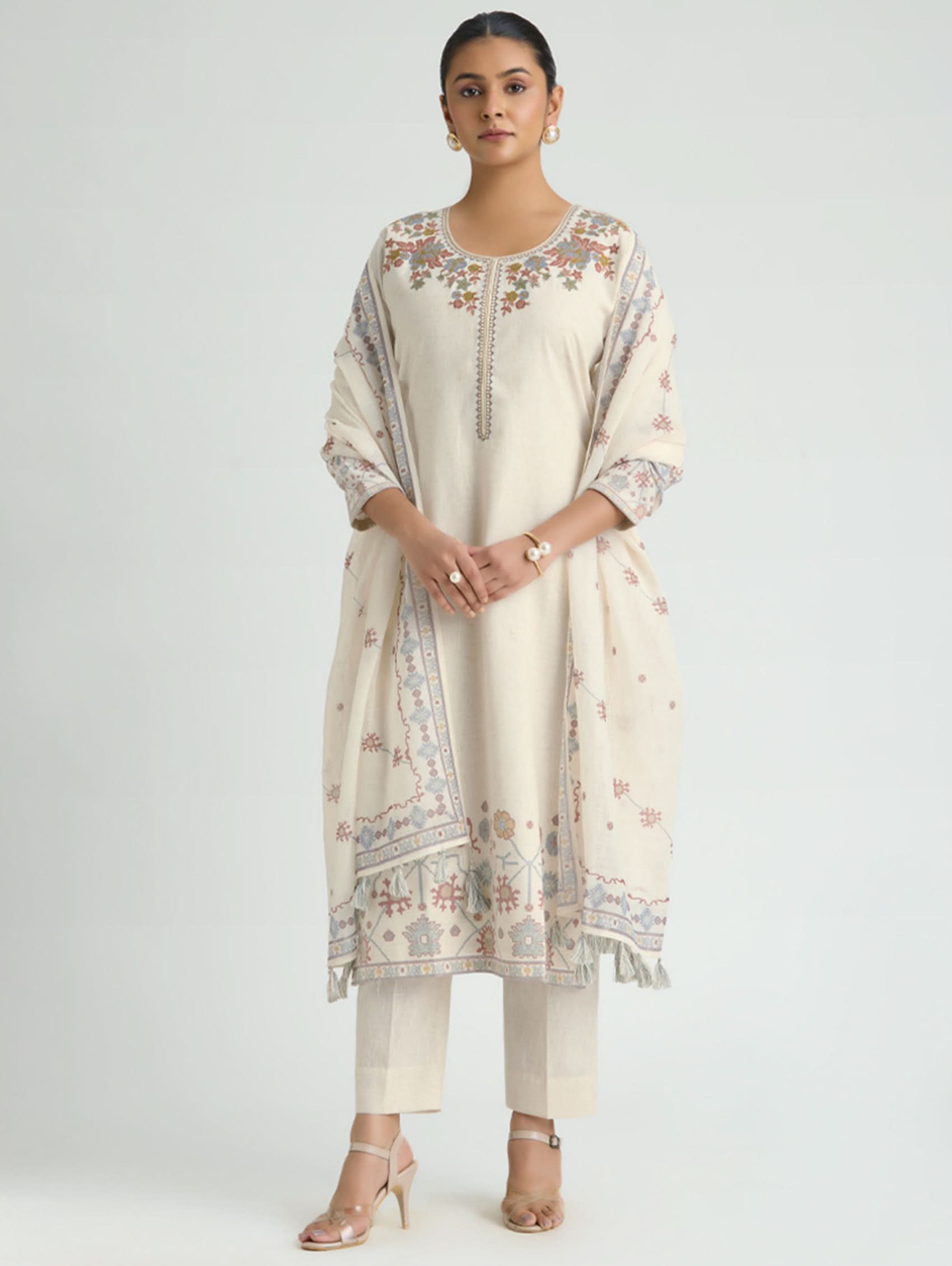 Woman wearing a cream-colored traditional outfit with floral patterns on a white background