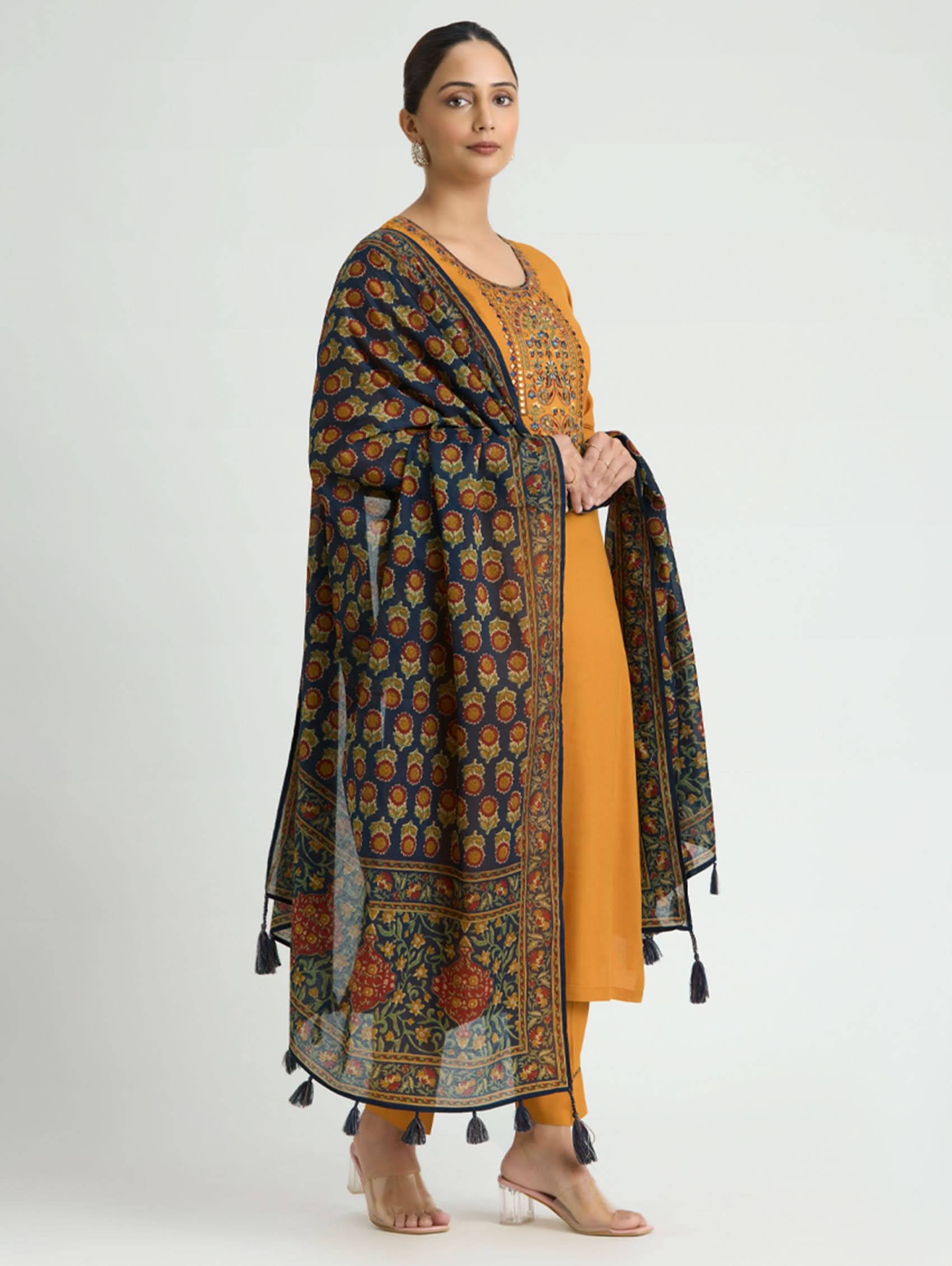 Woman wearing a mustard yellow kurta with a patterned black dupatta on a white background