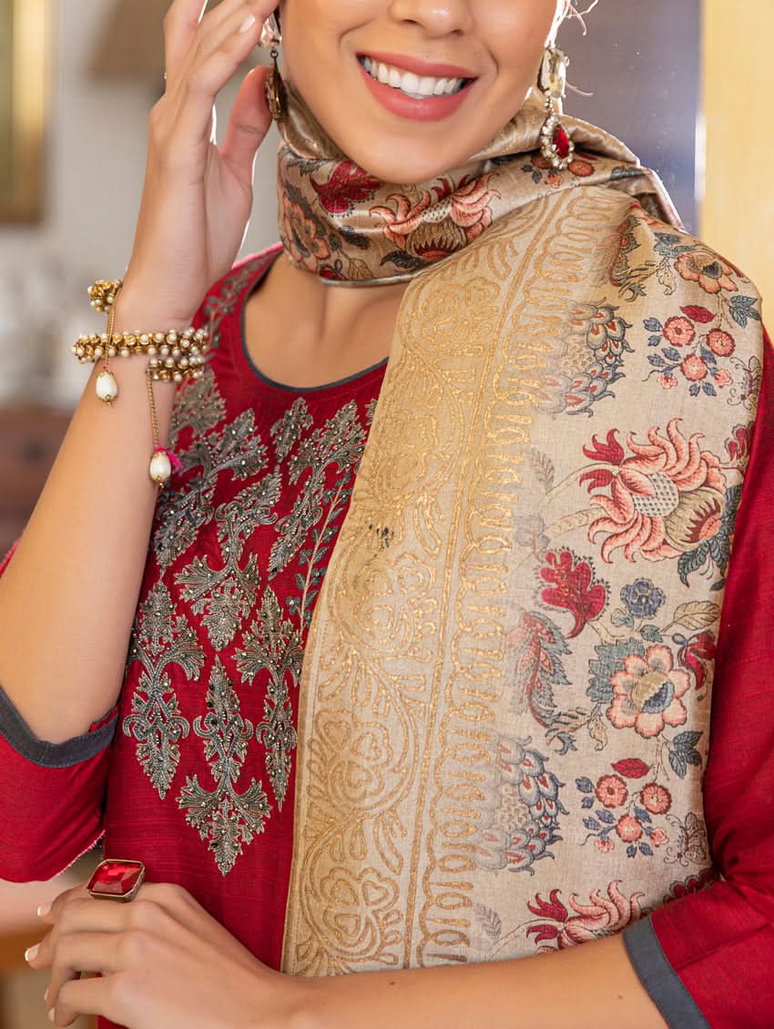 A woman modeling a red raw silk suit set with hand embroidery, consisting of a kurta, pants, and a dupatta with a floral design.