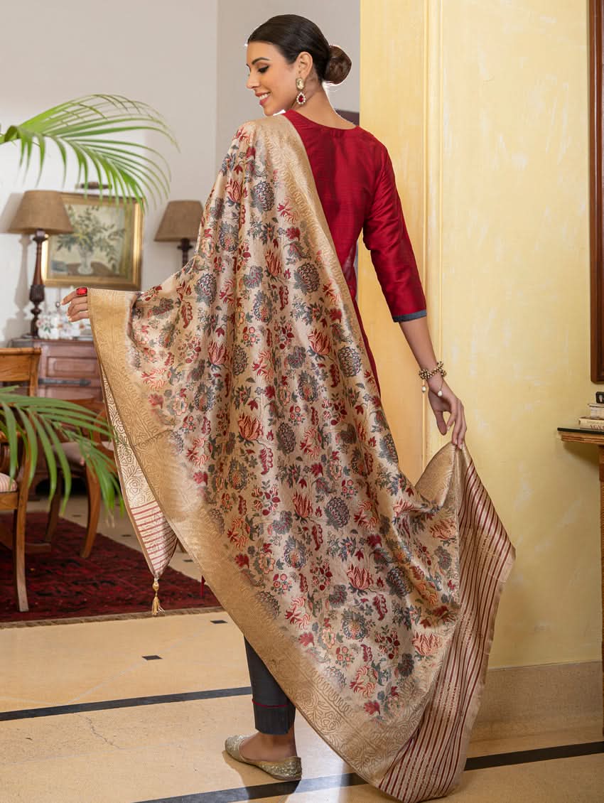 A woman modeling a red raw silk suit set with hand embroidery, consisting of a kurta, pants, and a dupatta with a floral design.