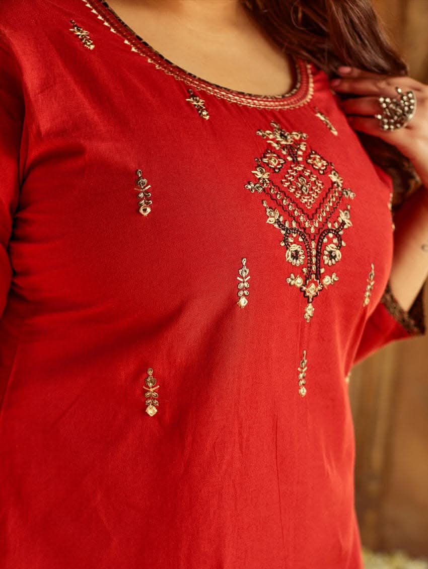 A woman standing in a beautifully decorated room wearing a red handloom cotton kurta with round neckline and three fourth sleeves, featuring computerised thread embroidery.