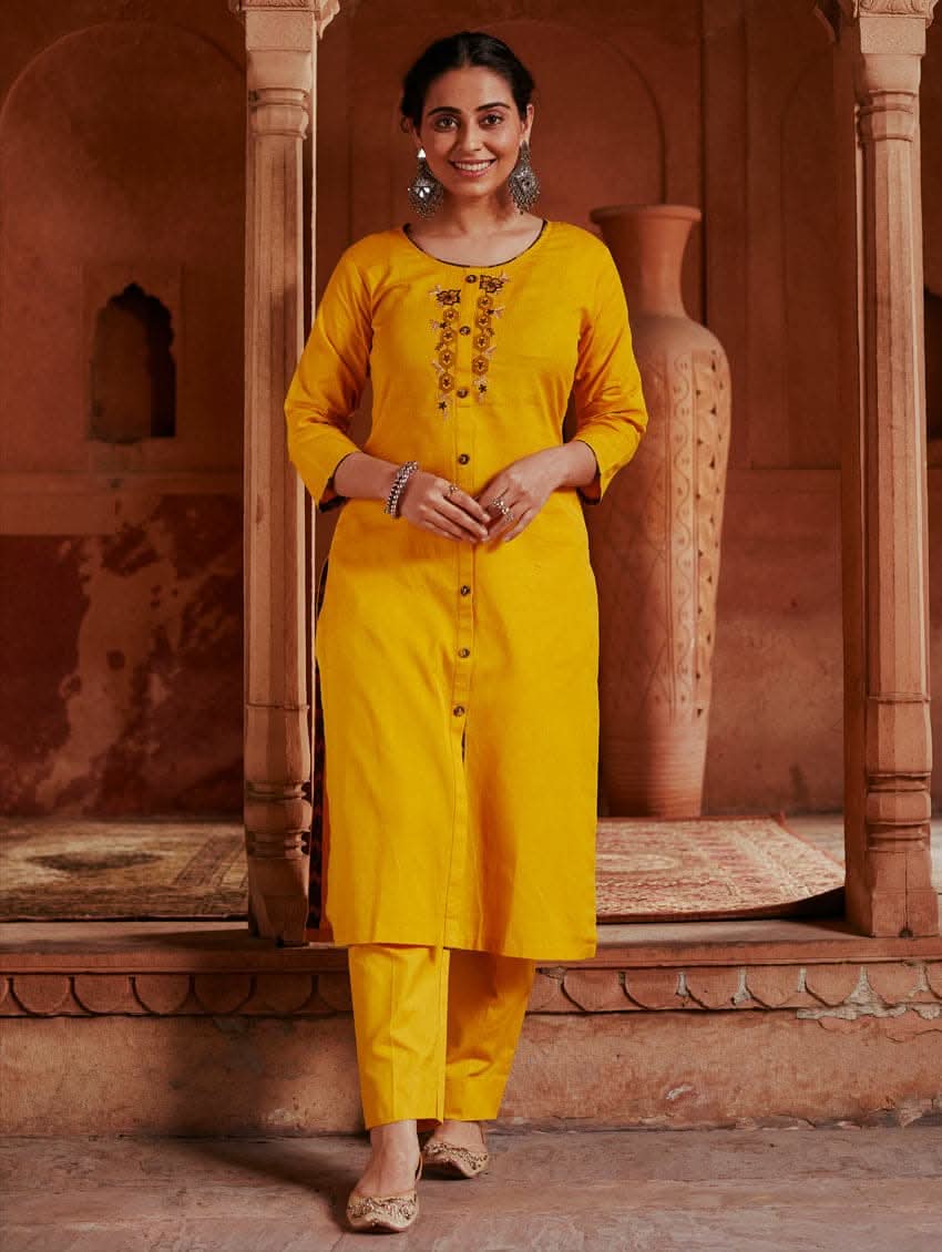 A woman standing in a beautifully decorated room wearing a red handloom cotton kurta with round neckline and three fourth sleeves, featuring computerised thread embroidery.