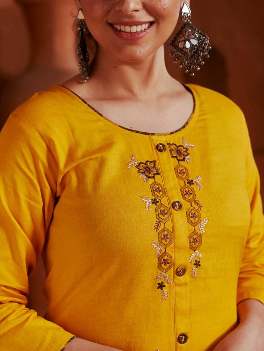A woman standing in a beautifully decorated room wearing a red handloom cotton kurta with round neckline and three fourth sleeves, featuring computerised thread embroidery.