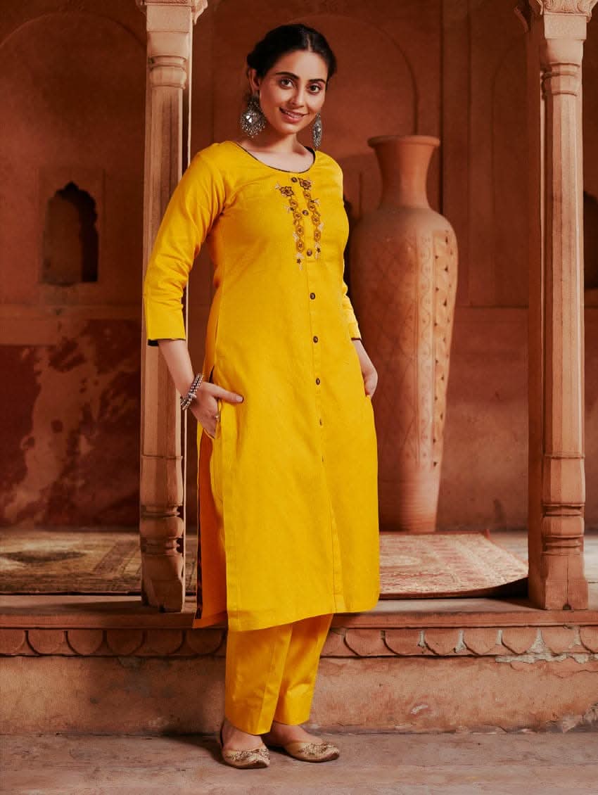 A woman standing in a beautifully decorated room wearing a red handloom cotton kurta with round neckline and three fourth sleeves, featuring computerised thread embroidery.