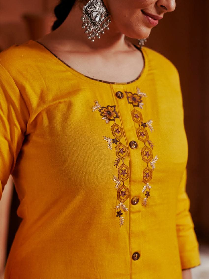 A woman standing in a beautifully decorated room wearing a red handloom cotton kurta with round neckline and three fourth sleeves, featuring computerised thread embroidery.