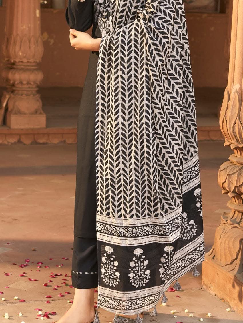 A woman wearing a black rayon suit set with embroidery on the kurta, consisting of a solid colored kurta with pants and a printed mul dupatta.