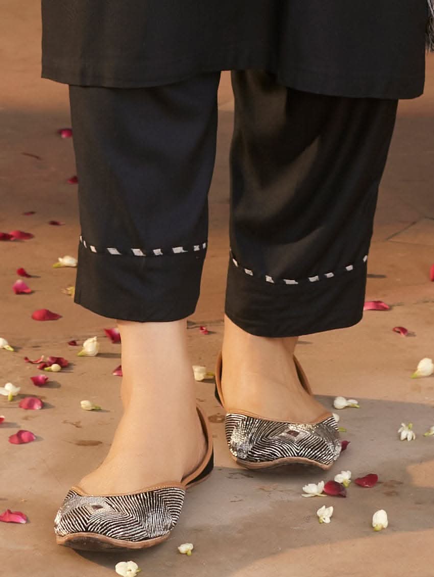 A woman wearing a black rayon suit set with embroidery on the kurta, consisting of a solid colored kurta with pants and a printed mul dupatta.
