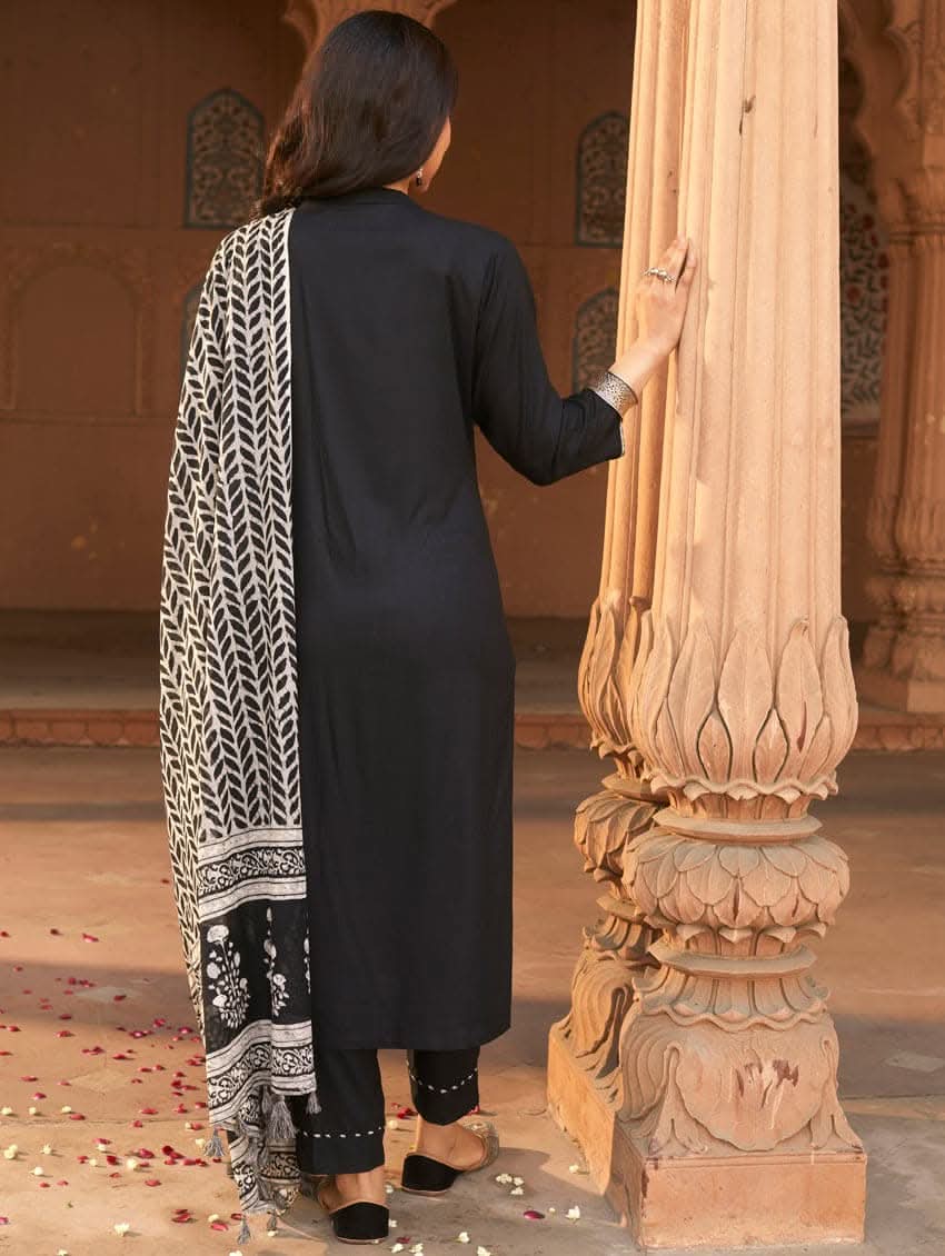 A woman wearing a black rayon suit set with embroidery on the kurta, consisting of a solid colored kurta with pants and a printed mul dupatta.