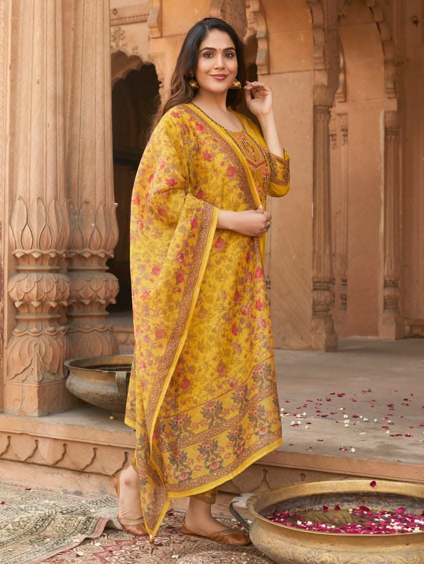 A woman wearing a yellow linen silk suit set with embroidery, consisting of a kurta, pants, and a dupatta.