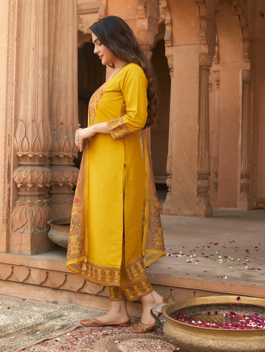 A woman wearing a yellow linen silk suit set with embroidery, consisting of a kurta, pants, and a dupatta.