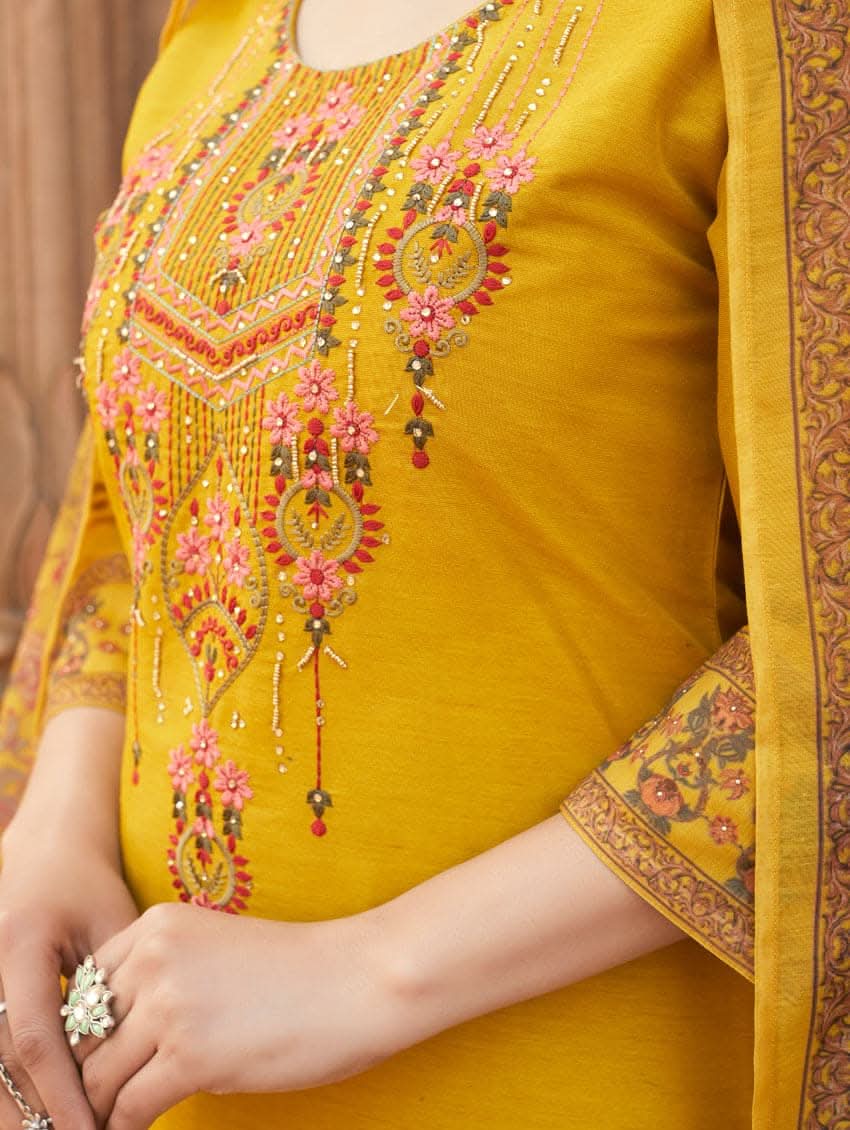 A woman wearing a yellow linen silk suit set with embroidery, consisting of a kurta, pants, and a dupatta.