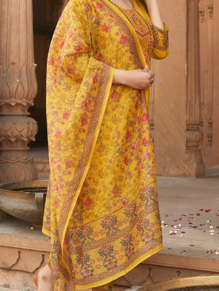A woman wearing a yellow linen silk suit set with embroidery, consisting of a kurta, pants, and a dupatta.