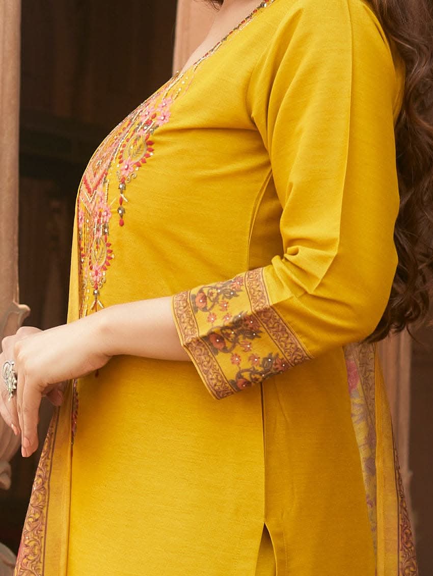 A woman wearing a yellow linen silk suit set with embroidery, consisting of a kurta, pants, and a dupatta.