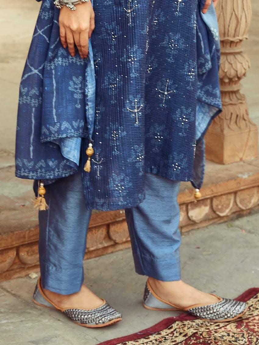 A woman wearing a traditional Digitally Printed Blue Silk Suit Set with a kurta, pants, and dupatta in a historic building with intricate architectural details.