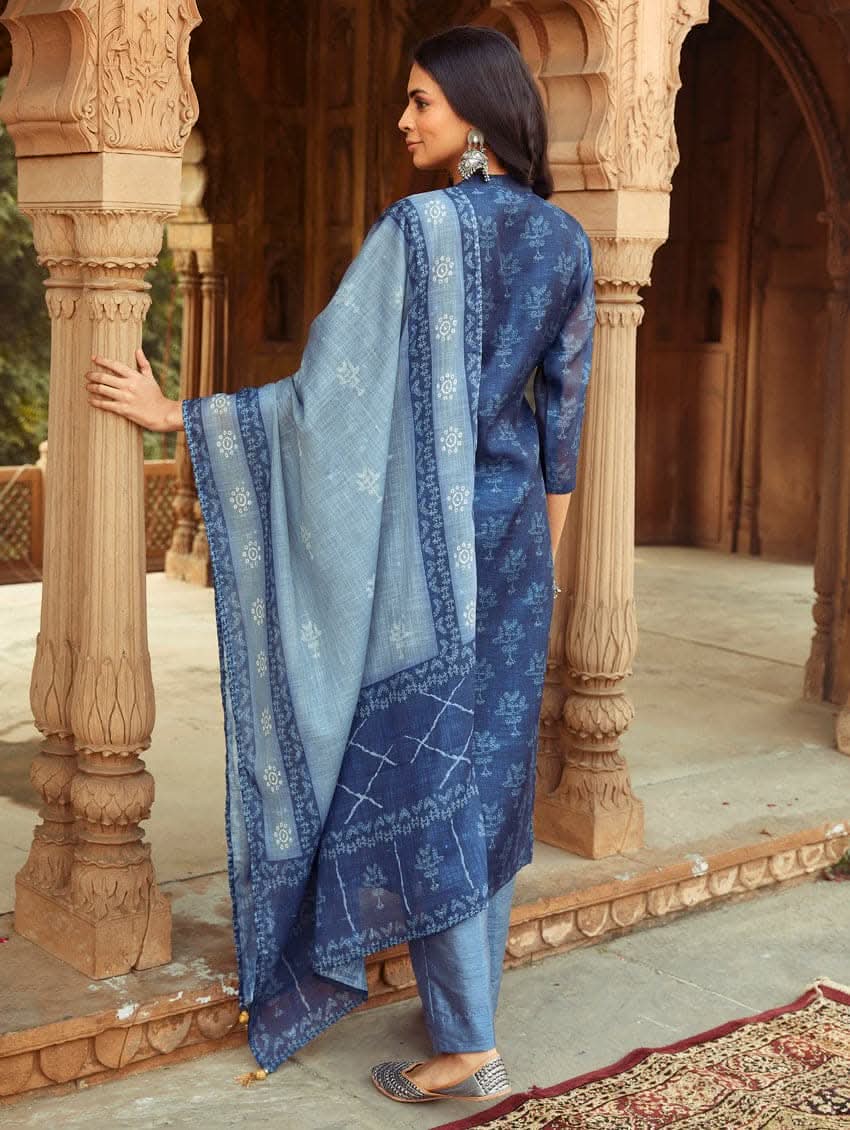A woman wearing a traditional Digitally Printed Blue Silk Suit Set with a kurta, pants, and dupatta in a historic building with intricate architectural details.