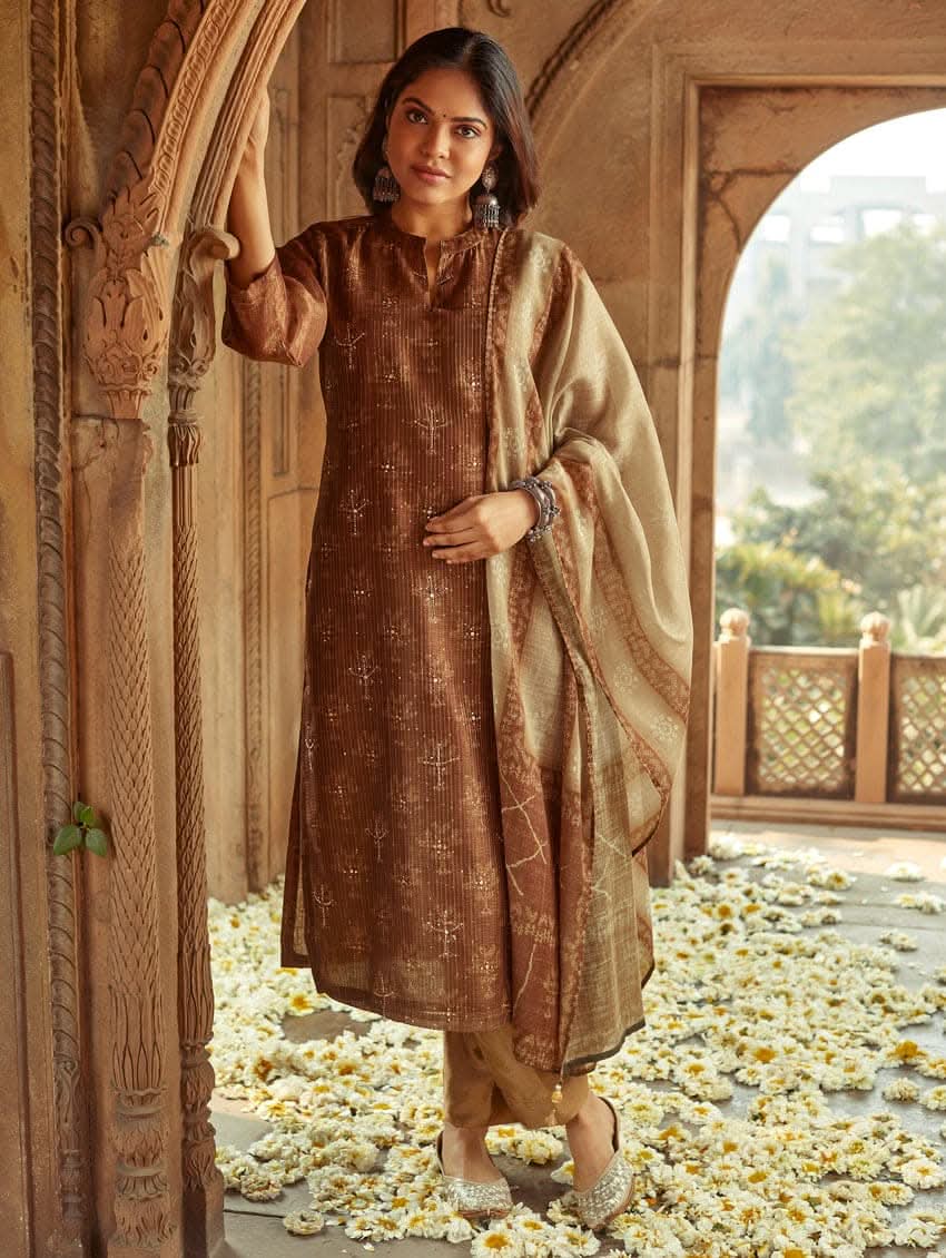 A woman wearing a traditional Digitally Printed Silk Suit Set with a kurta, pants, and dupatta in a historic building with intricate architectural details.