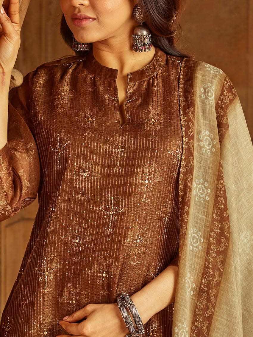 A woman wearing a traditional Digitally Printed Silk Suit Set with a kurta, pants, and dupatta in a historic building with intricate architectural details.