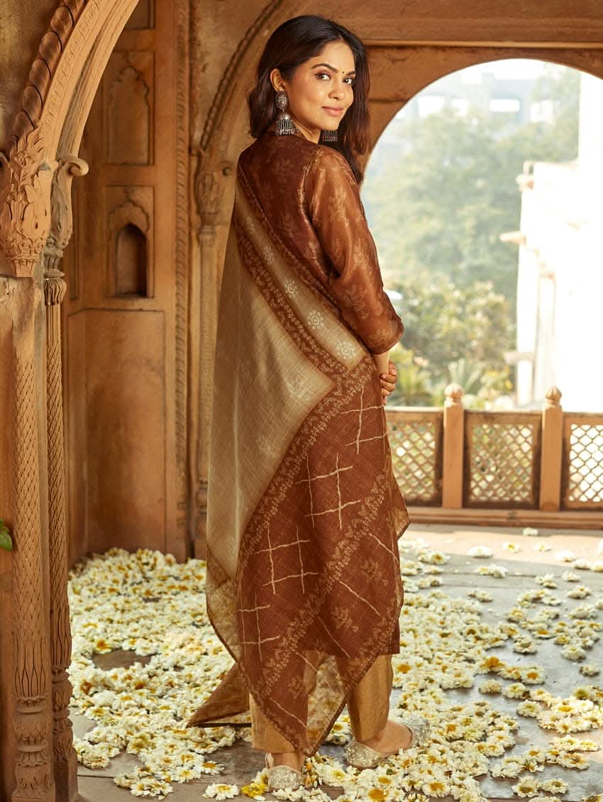 A woman wearing a traditional Digitally Printed Silk Suit Set with a kurta, pants, and dupatta in a historic building with intricate architectural details.