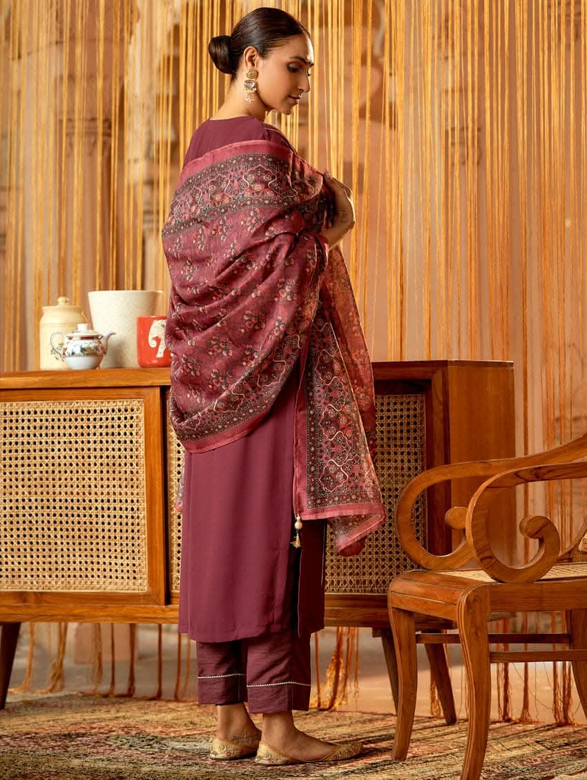 A woman standing in an elegant pose wearing a purple georgette suit with embroidered details and a dupatta with digital printed chanderi silk.