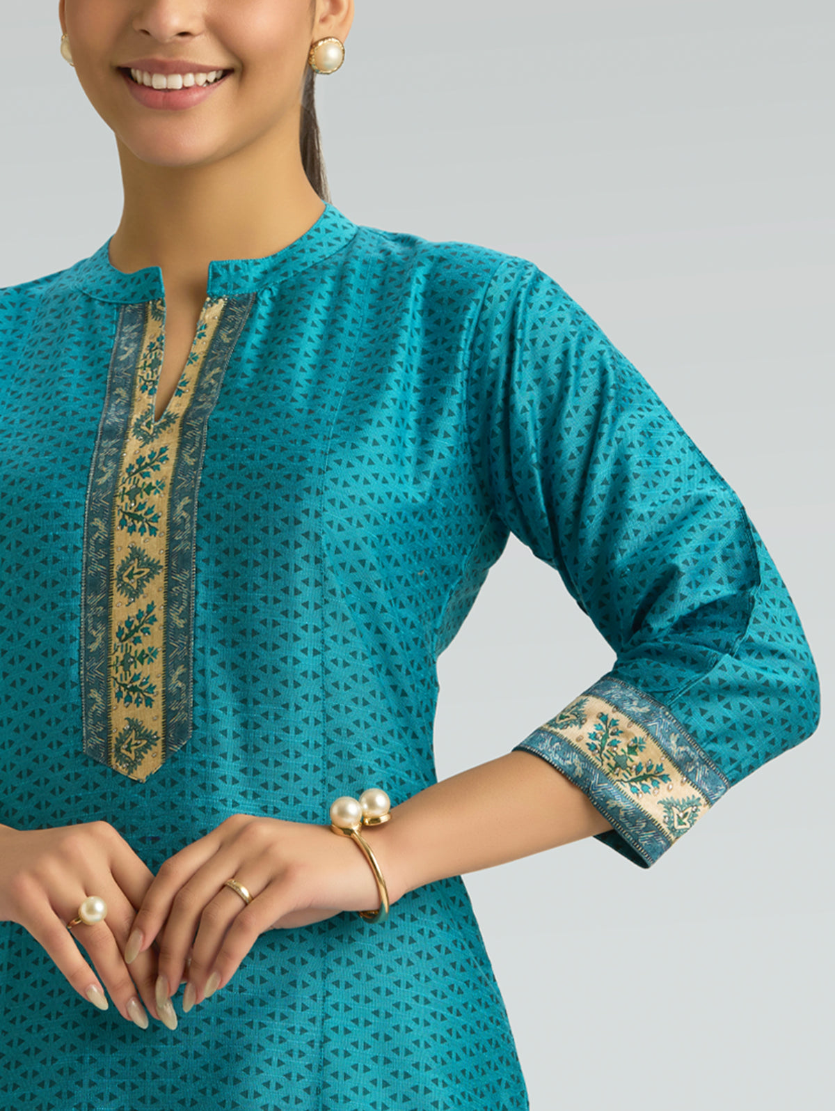Close-up of dark cyan printed kurta neckline with gold-trim cuff and placket