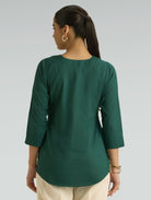 Woman wearing a green top with a plain background