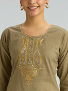 Woman wearing a brown kurta with intricate gold embroidery on a plain background