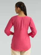 Person wearing a pink long-sleeve top on a gray background