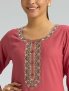Pink embroidered top worn by a model on a gray background