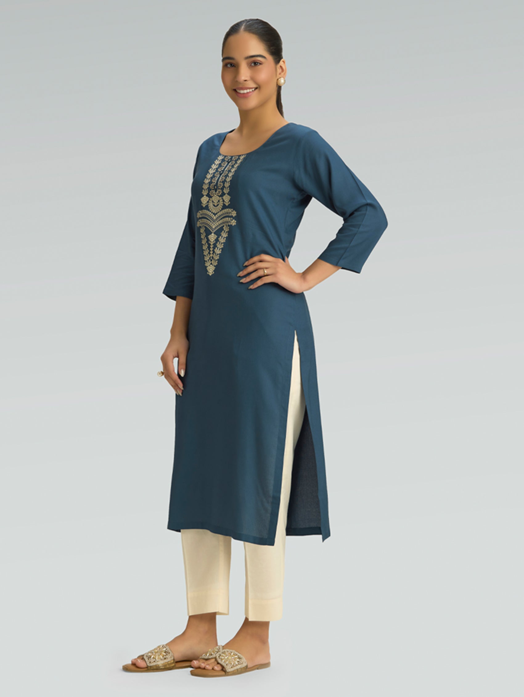 Woman wearing a blue kurta with white pants on a gray background