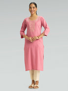 “A woman dressed in a straight-fit pink kurta featuring a round collar and intricate computerized thread embroidery, set against a gray background.”