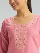 Close-up of a pink embroidered garment with a gray background