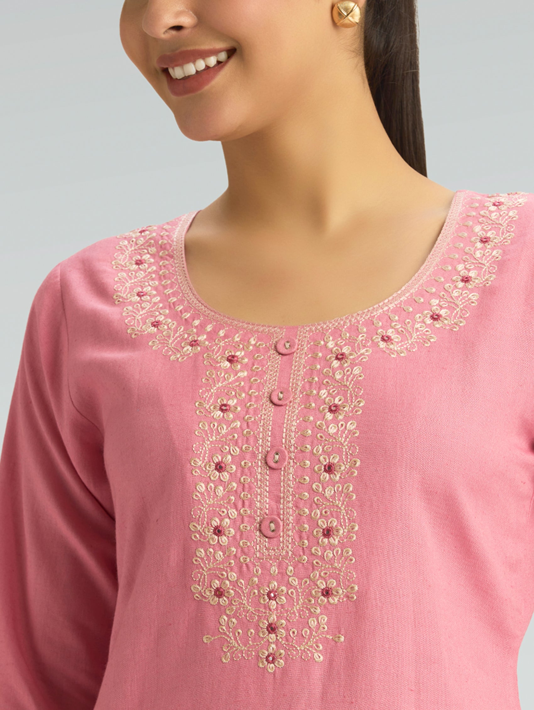 Close-up of a pink embroidered garment with a gray background
