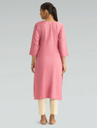 “A woman dressed in a pink kurta paired with white pants, captured in a graceful back pose on a light gray background.”