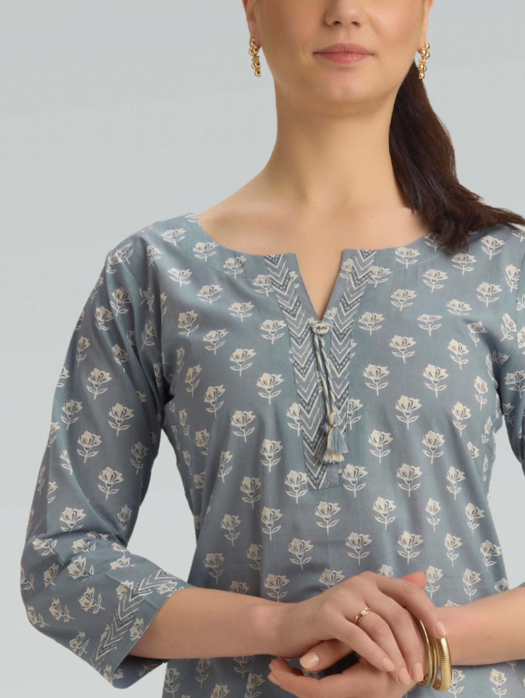 Woman wearing a blue floral patterned top against a gray background