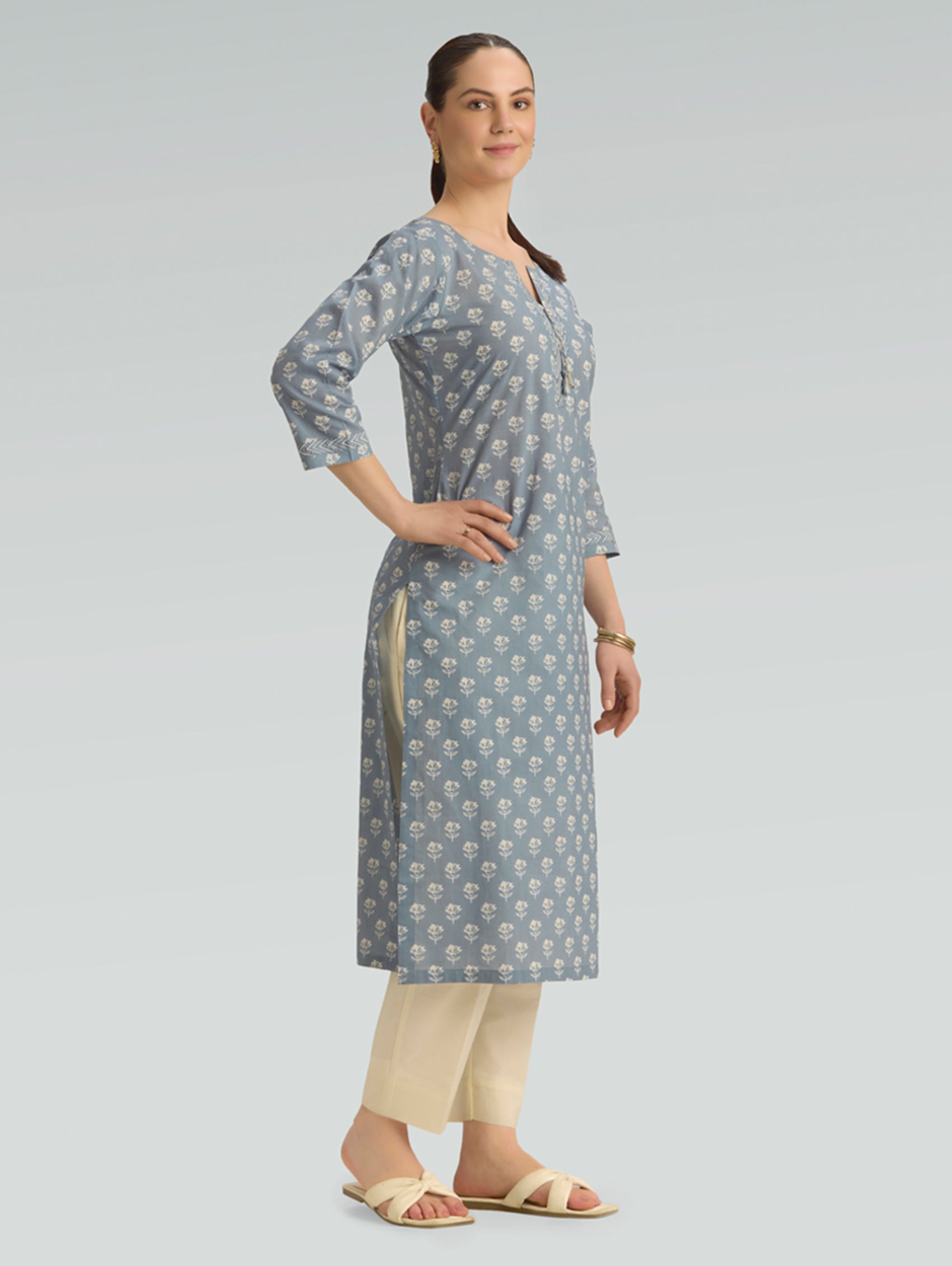 Woman wearing a gray patterned kurta with beige pants on a light gray background